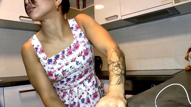 Sexy brunette wife Lena Coxx flashes her shaved pussy in a mini dress in the kitchen