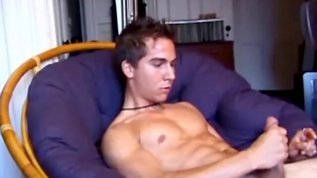 Brocks pops in a porn video and starts to strip. The man sports a hard cock, stroking it before exploding on his face and chest.