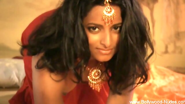 Dark-haired Indian mistress glows in red silk and gold under warm candlelight