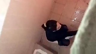 Asian woman spied over the toilet wall taking a pee