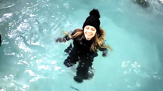 Wetlook girl with winter clothes swims in the pool