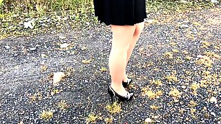 A girl walks in nature in black shoes and tights pantyhose under a skirt