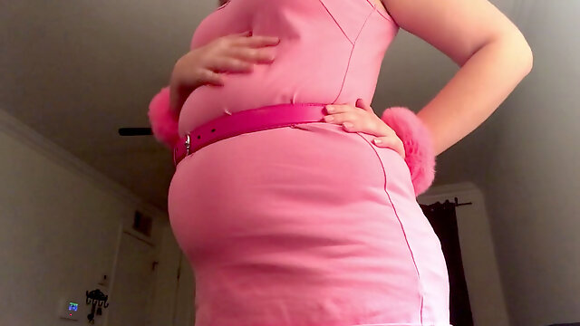 Blond sticking her big round belly in pink costume