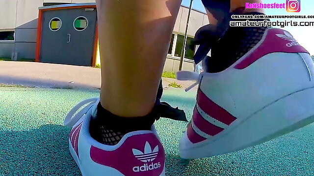 Girl in red Adidas Superstars does shoeplay, dipping fishnet socks 