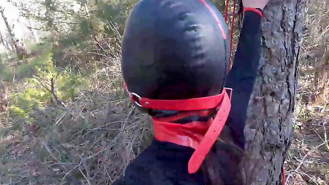 Tied up to a tree, outdoors in sexy clothes, ball gagged