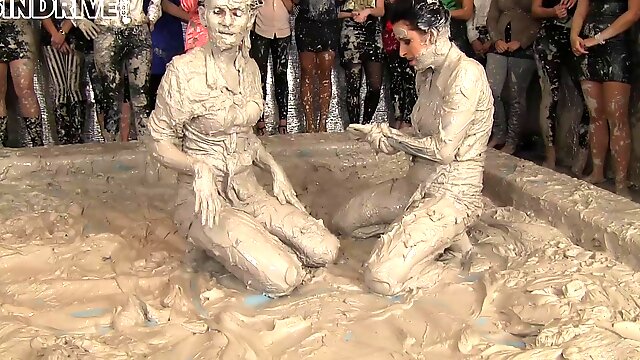 Leather-clad brunette with a sexy body having a catfight in a mudbath