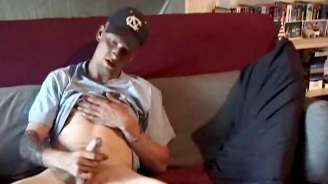 Young amateur Brandon lays back on the couch and takes off his pants. While watching a porn video, he rubs his cock hard and fingers his ass.