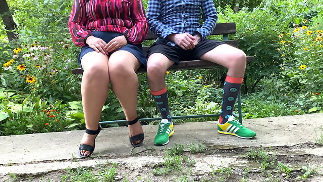 Luxurious stepmother helps her stepson to pee while sitting in the park on a bench