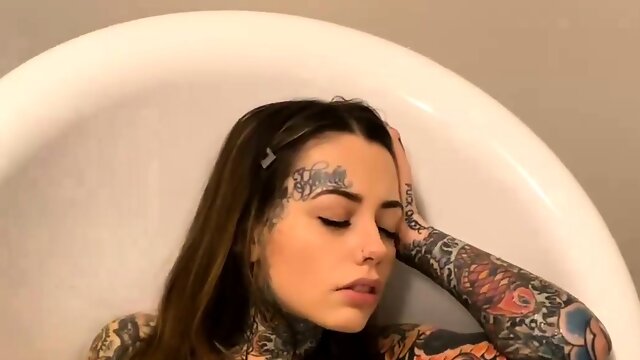 Buxom tattooed brunette making herself cum in the bathtub