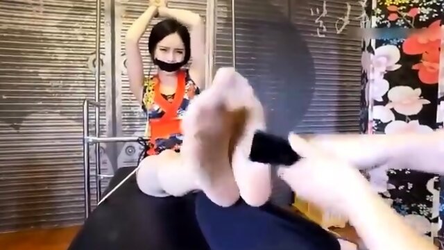 Restrained Asian beauty getting her marvelous feet tickled