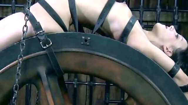 Well shaped black haired babe Elise Graves spins on BDSM wheel