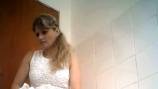 Fine curvaceous blonde lady in white dress filmed in the toilet room