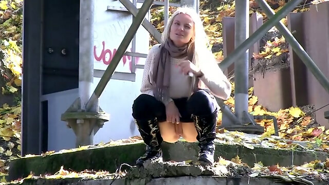 Blonde chick climbs on the concrete wall and urinates