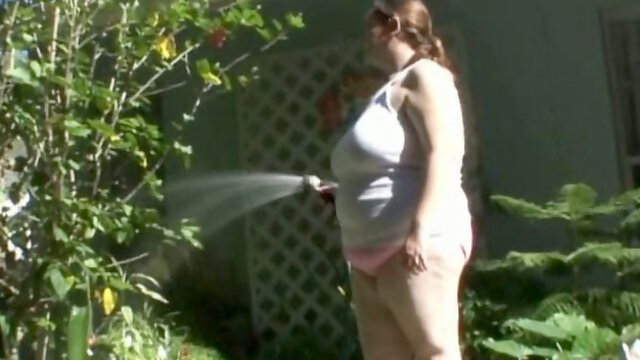 Horny BBW whore plays with a hose in the garden while stripping