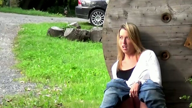 Blond haired pregnant chick sits behind the wooden barrel and pisses