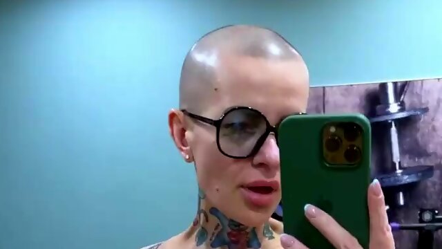 Bald headed MILF with tattooed body masturbates pussy in the gym