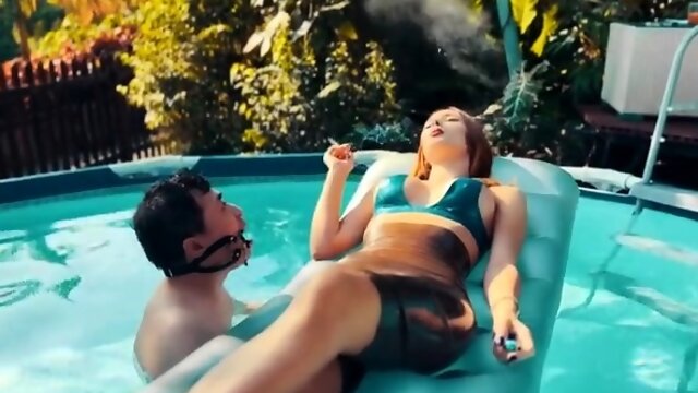 Ravishing redhead mistress punishing her slave in the pool