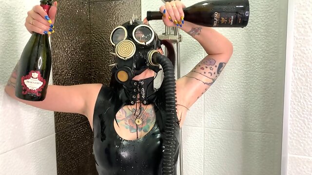 Dominatrix Nika in a gas mask pours wine over her latex body. Latex fetish