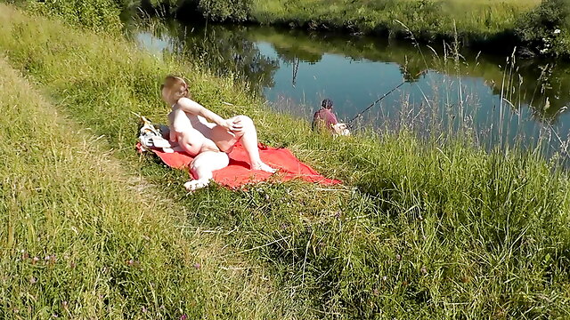 Nudist beach. Public nudity. Sexy MILF without panties and bra sunbathes naked is not shy about fisherman. Naked in public. Milf